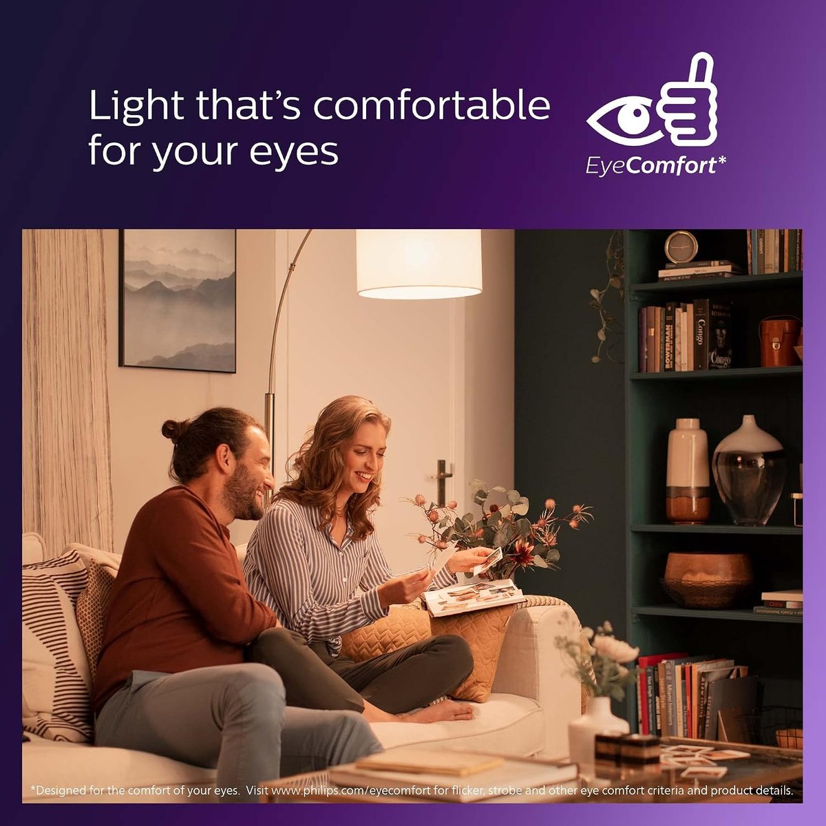 Pareja leyendo en el salón bajo la luz cálida y sin parpadeo de una lámpara con bombilla LED Philips EyeComfort